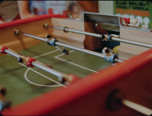 People are playing a game on the foosball table