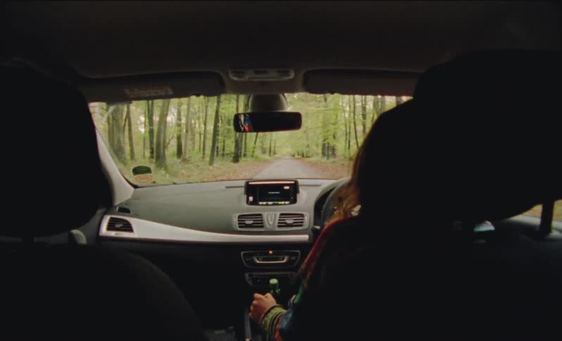 Woman driving on a road through a forest area