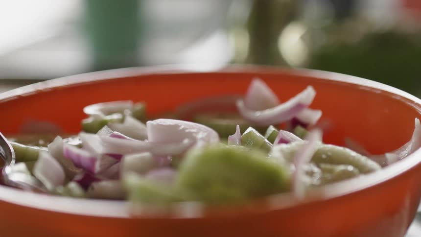 Peppers and onions are in an orange bowl