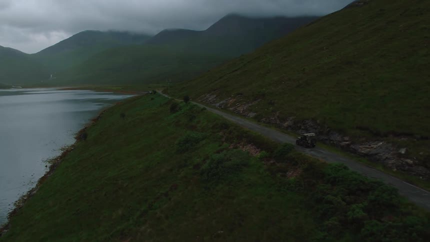 A Jeep drives down a lakeside road