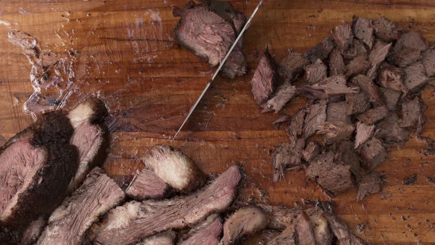A man cuts pieces of grilled steak