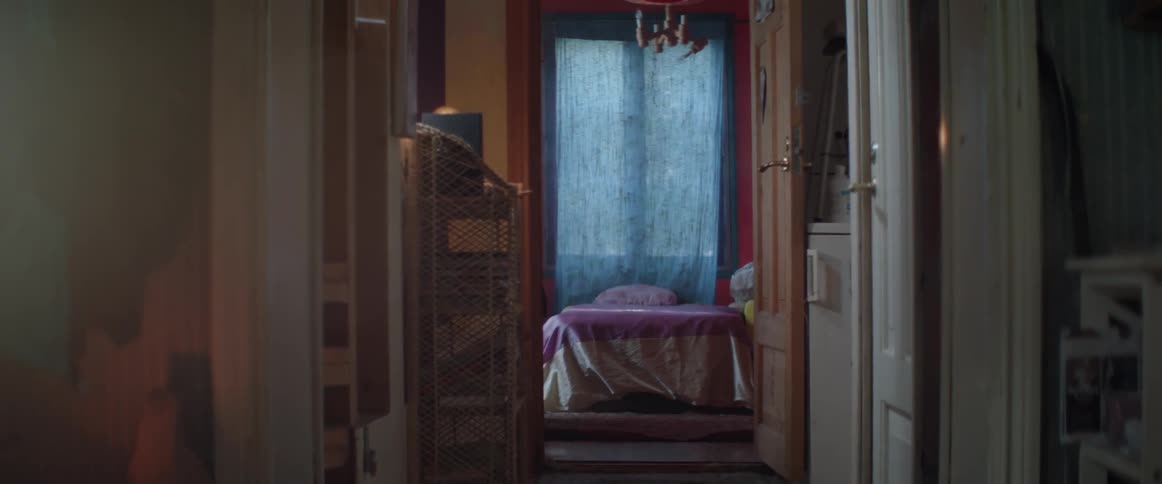 A wide view looking down a dark home hallway into a rustic bedroom scene