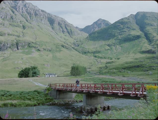A hiker wearing a backpack crosses a bridge