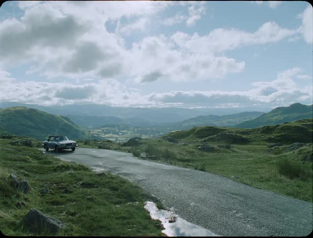 The car comes up around the turn down the small road