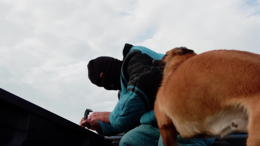 The dog is biting his arm and dragging him around