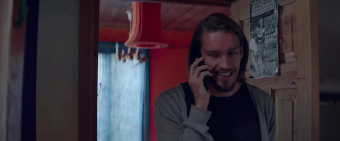 A happy young man smiles cheerfully while having a pleasant mobile phone conversation.