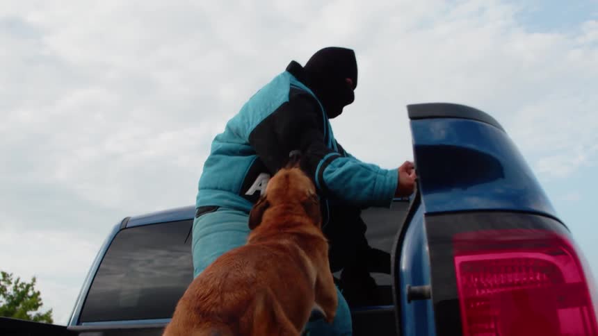 The dog is biting the person wearing heavy pads