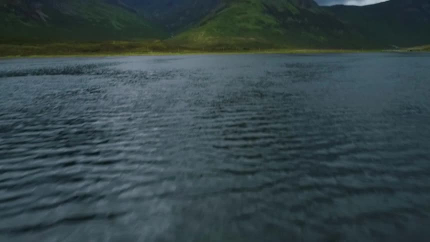 The tide flows on the water near tall mountains