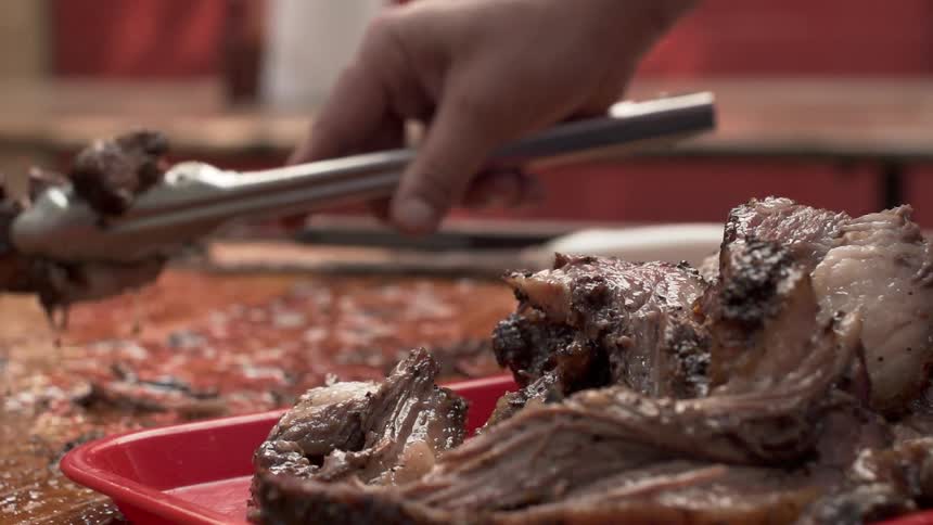 A man uses tongs to lift up cut beef