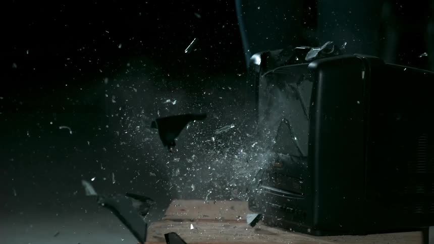 A person smashes a television with a sledgehammer
