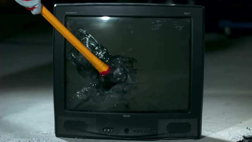 Someone smashes a television with a sledge hammer