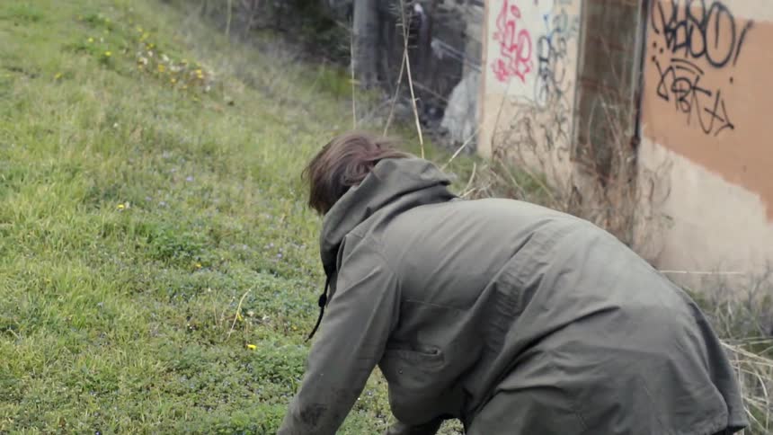 A person climbs up a hill on their hands and knees