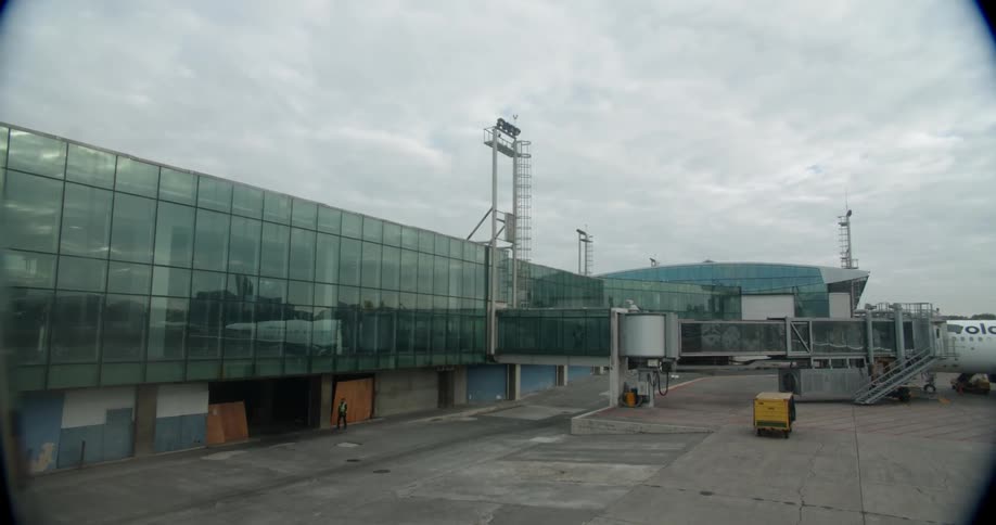 An airport worker walks outside of a glass building