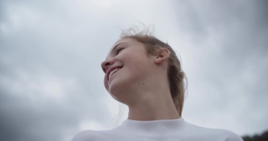 A girl looks around laughing on a windy day