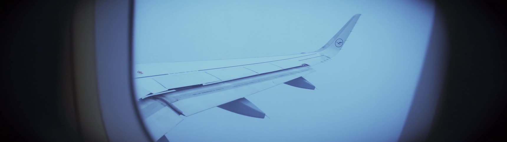 A light is flashing on a an airplane wing as it flies at dusk