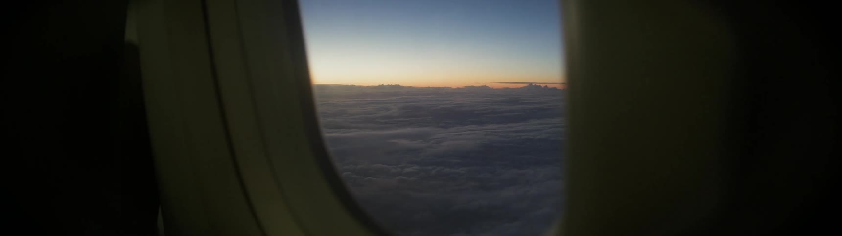 The plane is flying high above the clouds at sunset