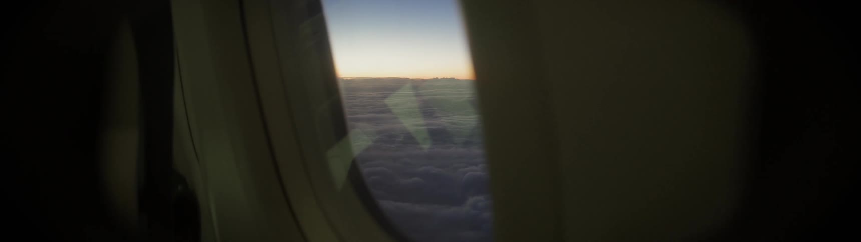 Airplane flies over land under a blue sky