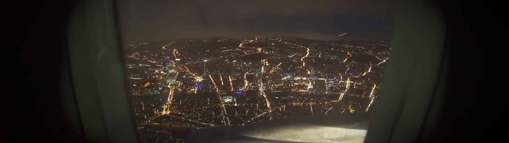 An airplane flies over a city at night