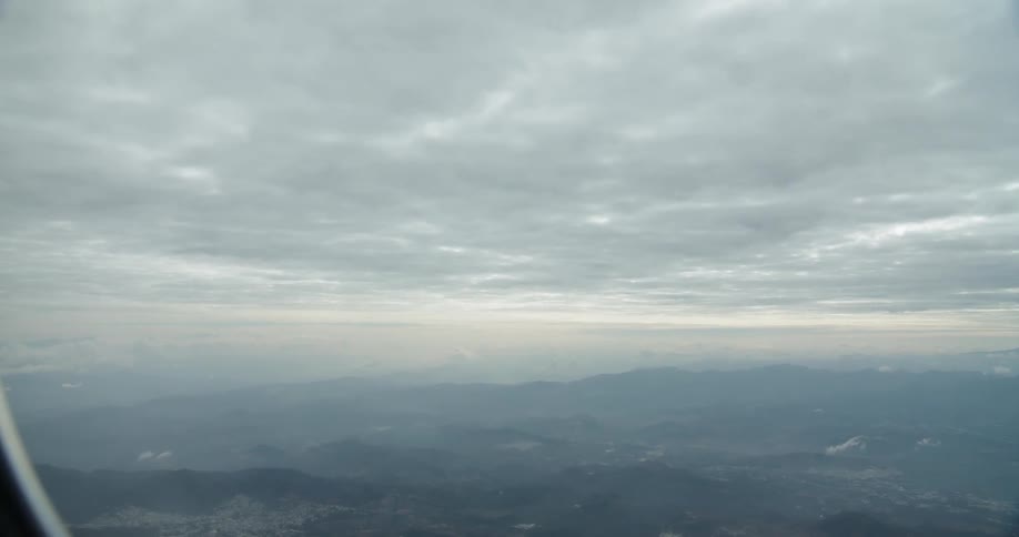 Airplane flies under a cloudy sky
