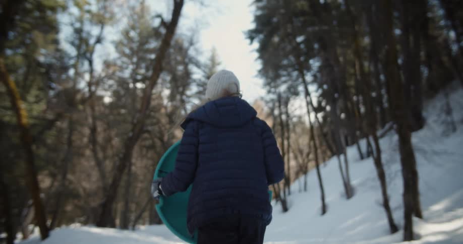 A girl runs before turning around to jump on her sled