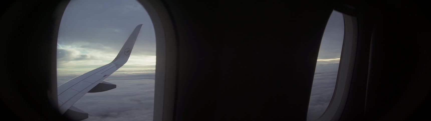 The wing of an airplane and clouds are visible through the window