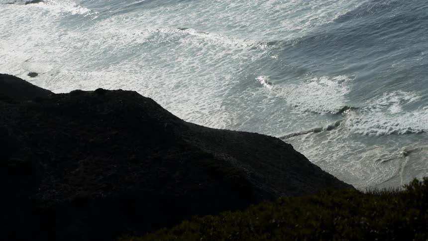 The waves crash hard against the rocks on the shore