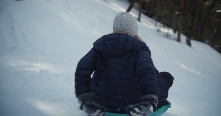 A girl slides down the snow filled hill