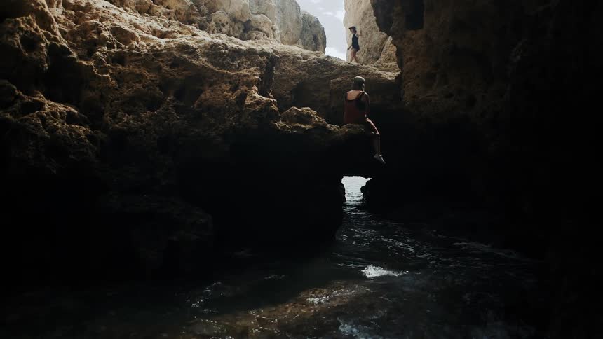 A person walks over the rocks on the shore