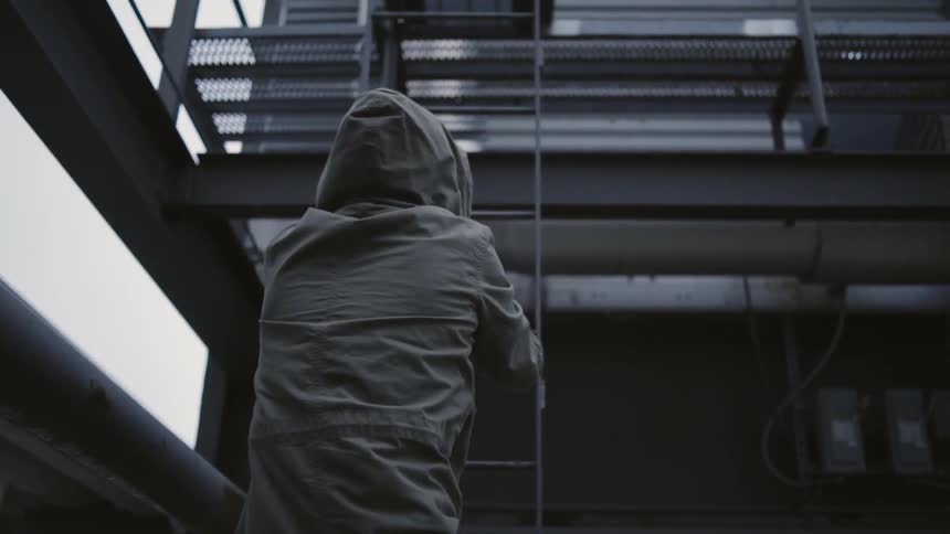 A man climbs a lader in a city
