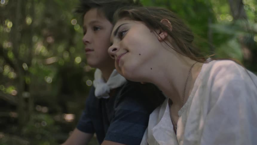 A boy and girl are sitting together in the forest