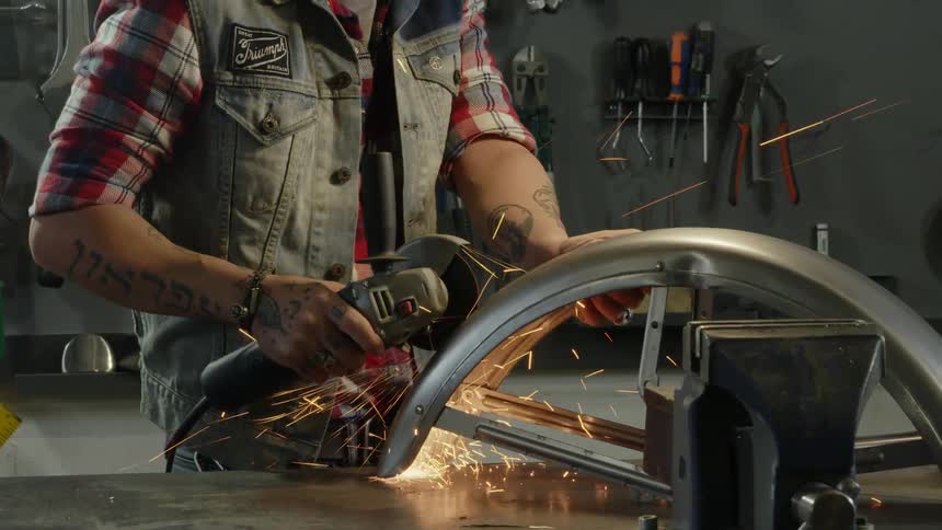 Man in a workshop uses a grinding blade on a bicycle part