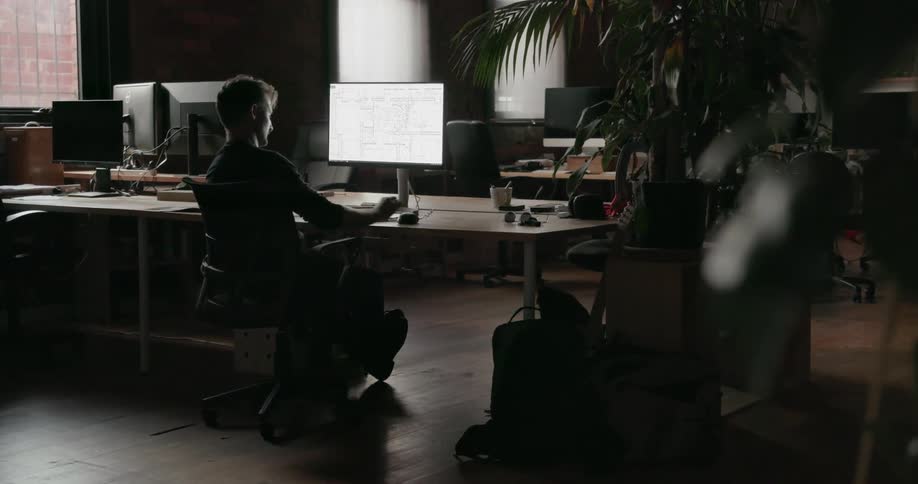 Man looks at computer monitor as he sits at a desk