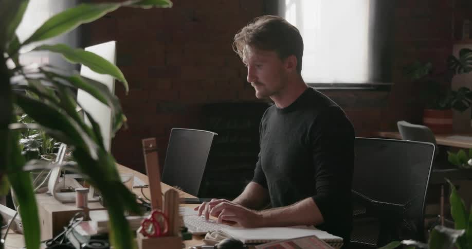 Man types on a keyboard as he looks at a monitor