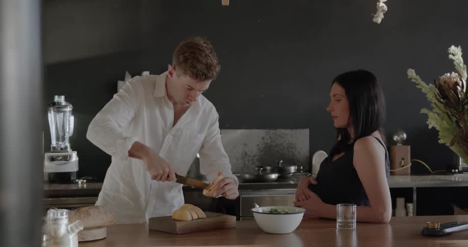 Man slices fruit as a woman watches