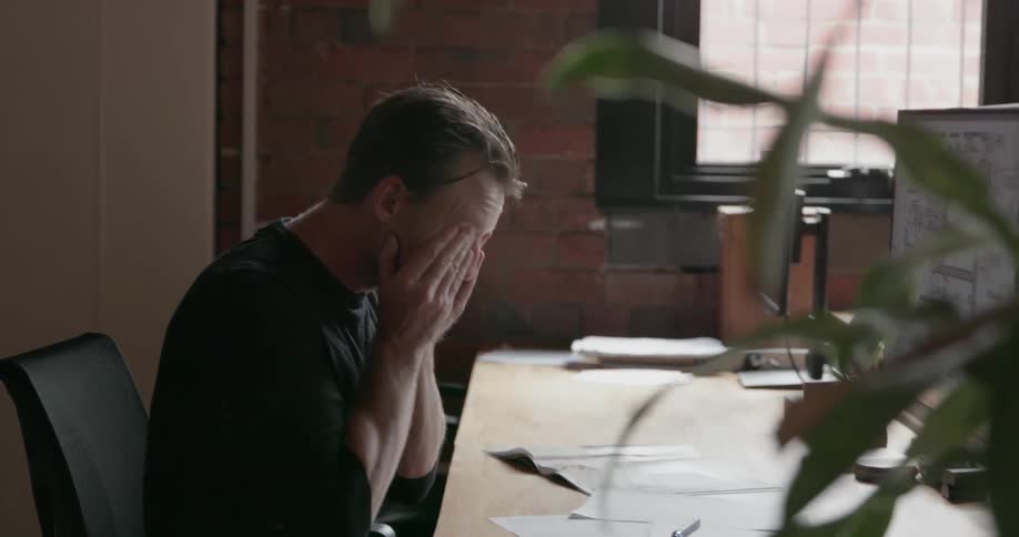 A man is working in the office, and rubs his face
