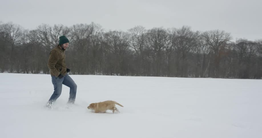 A man runs with a dog in a snowy field