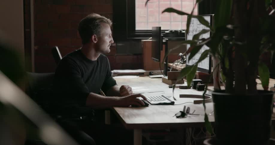 Man using his mouse to navigate his computer in a dark area