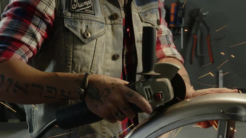 A man is cutting a large piece of metal with a tool