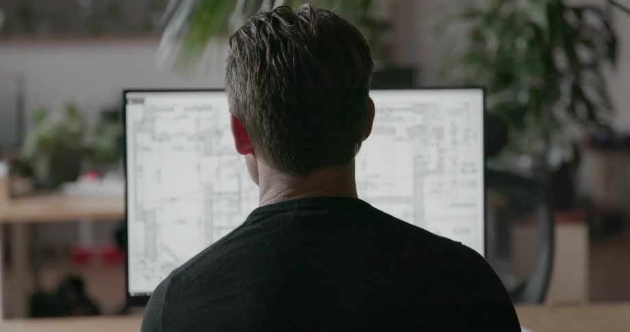 A man looks at a blueprint on the monitor