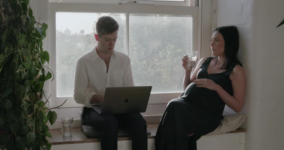 A man and woman sit by the window talking