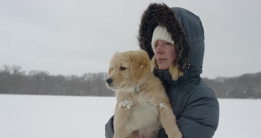 A woman is holding a puppy as she stands outside on a winter day