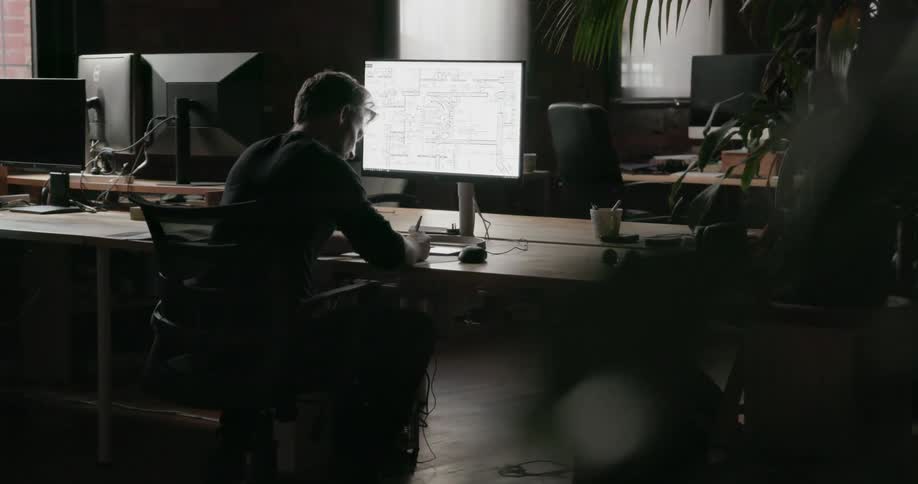 A man is working at his desk in the dark office