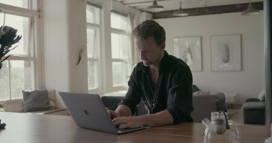 A man types on a laptop at home