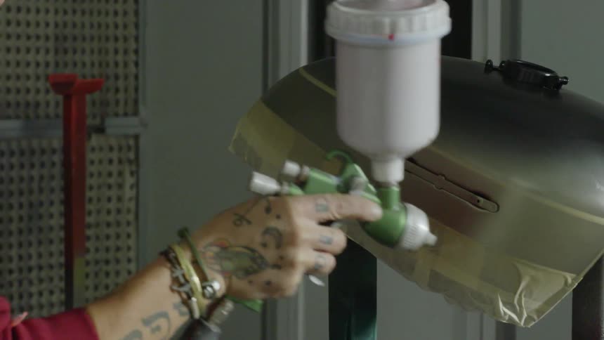 A man is spray painting a metal shell