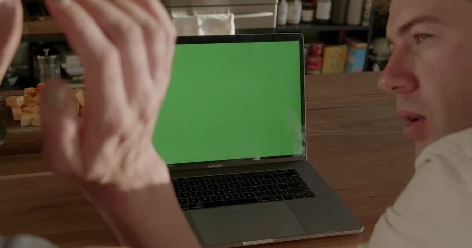 Two people sit at a laptop talking
