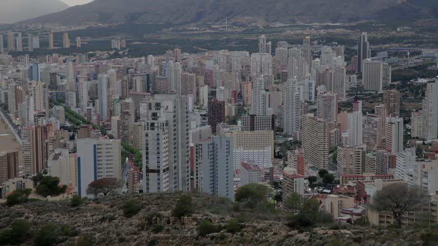 Past the hill is a city with many tall buildings