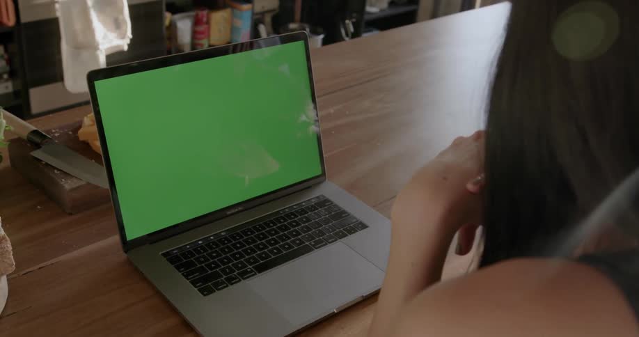 A woman is looking at a laptop sitting on a table