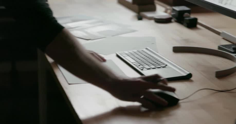 A man is working at a computer and looking at notes inside in daylight