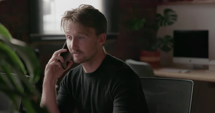 Man sits in an office chair talking on a phone