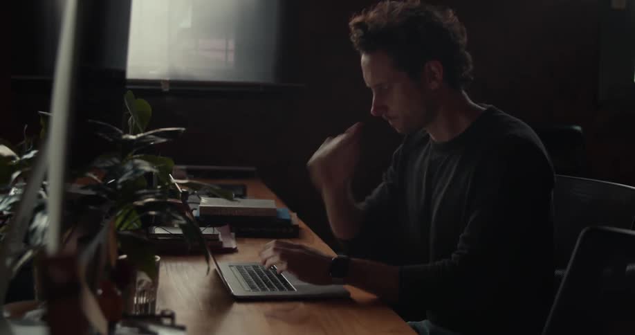 A man sits at a desk using a laptop